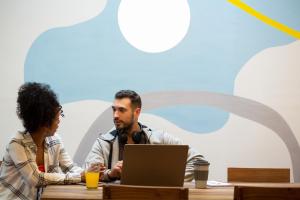 a man and woman sitting at a table with a laptop at Casa Franca Recoleta Hostel in Buenos Aires