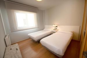a small room with two beds and a window at BICOS ao MAR in Rianjo