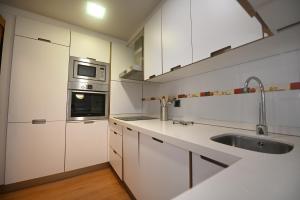 a white kitchen with a sink and a microwave at BICOS ao MAR in Rianjo