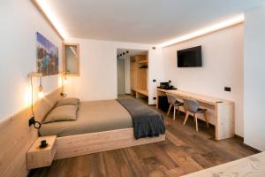 a bedroom with a bed and a desk and a table at BORMIO N'JOY in Bormio
