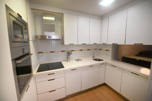 a kitchen with white cabinets and a sink and a microwave at BICOS ao MAR in Rianjo +2 photos