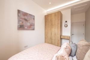 a bedroom with a bed and a wooden cabinet at The Pocklington - The Abbey Suite in Leicester