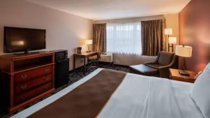 a hotel room with a bed and a flat screen tv at SureStay Plus Hotel by Best Western Auburn in Auburn