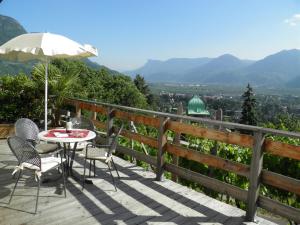 eine Terrasse mit einem Tisch, Stühlen und einem Sonnenschirm in der Unterkunft Appartementhaus Linter in Dorf Tirol