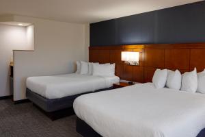 una camera d'albergo con due letti con lenzuola bianche di Courtyard by Marriott Oklahoma City North/Quail Springs a Oklahoma City