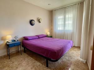 een slaapkamer met een paars bed en een raam bij Rocamaura I D 1-2 in L'Estartit +16 foto's
