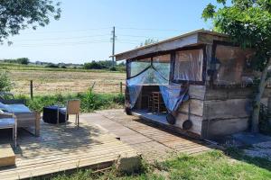 una pequeña casa de madera con una mesa y sillas en una terraza en logement dans Mas mobile home en Saint-Laurent-dʼAigouze