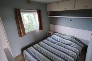 Habitación pequeña con cama y ventana en logement dans Mas mobile home en Saint-Laurent-dʼAigouze