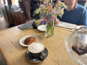 una mesa con una taza de café y un jarrón de flores en White Hart Hotel en Wiveliscombe