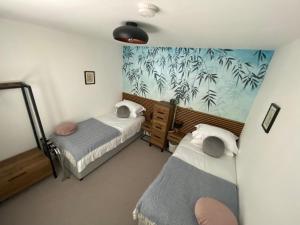 1 dormitorio con 2 camas y un mural de palmeras en Clements House Swanage, en Swanage