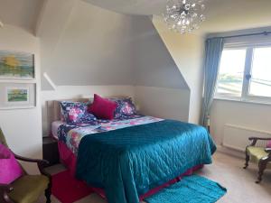 ein Schlafzimmer mit einem Bett mit einer blauen Decke und einem Kronleuchter in der Unterkunft Halekulani Devon Homestay in Torquay