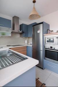 uma cozinha com armários azuis e um frigorífico de aço inoxidável em La casita de vanessa em Playa del Hombre