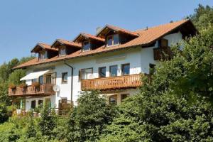 une grande maison blanche avec des balcons en bois et des arbres dans l'établissement Ferienwohnung-Panoramablick-1, à Bodenmais