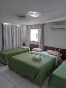 um quarto com três camas com lençóis verdes e uma janela em Pousada Familly -Praia de Tambaú -PB em João Pessoa