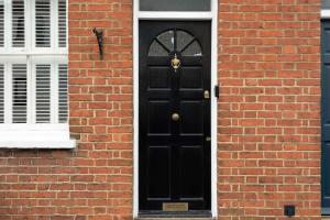 a black door on the side of a brick building at 30 Percent Off Monthly Stays - City Centre - 3 Bedrooms in St. Albans