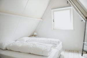 een bed in een witte kamer met een raam bij Boshuisje Rekem - Luka in Lanaken