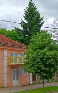 a tree in front of a house with a balcony at Жути ранац / Yellow Backpack in Boljevac