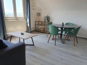 - un salon avec une table et des chaises vertes dans l'établissement GRENIER DES CIGOGNES, à Sélestat
