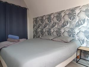 - une chambre avec un grand lit blanc et une tête de lit fleurie dans l'établissement GRENIER DES CIGOGNES, à Sélestat