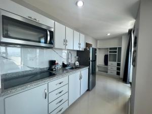 a kitchen with white cabinets and a stainless steel refrigerator at Hotel Tramonto Mazatlan in Mazatlán