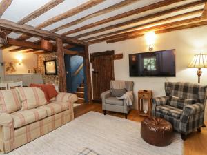 a living room with a couch and two chairs and a tv at Fox Den Cottage in Castle Combe
