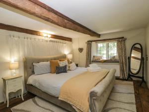 a bedroom with a large bed and a mirror at Fox Den Cottage in Castle Combe