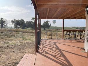 une terrasse couverte avec des chaises et une vue sur une montgolfière. dans l'établissement Modern wine country barn house, à Temecula