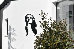 a mural of a woman on a wall next to a plant at Zoi Ayia Napa in Ayia Napa