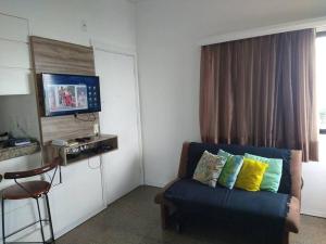 uma sala de estar com um sofá e uma televisão em Lindo Flat Beira Mar 401 em Fortaleza