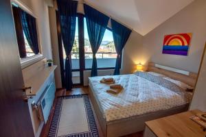 1 dormitorio con 1 cama con una pintura de arco iris en la pared en Мансарда с фантастични гледки и две спални en Chepelare