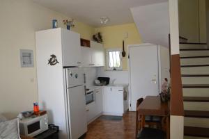a kitchen with white cabinets and a white refrigerator at Παραθαλάσσια μεζονέτα! in Kamena Vourla