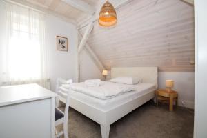 een kleine slaapkamer met een wit bed en een kroonluchter bij Willa Portus in Słupsk
