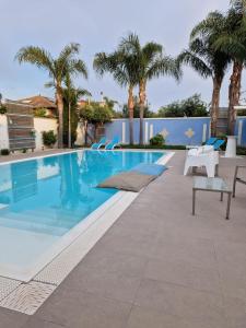 una piscina con sillas y palmeras en B&B Villa Eraclea en Villaggio Mosè