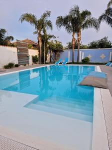 una piscina in una villa con palme di B&B Villa Eraclea a Villaggio Mosè