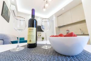 a bottle of wine and two wine glasses on a counter at Djukic Apartmani in Tivat