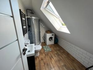 a bathroom with a toilet and a sink and a window at Chatka Rybaka - wygodny dom z podwórkiem in Łeba