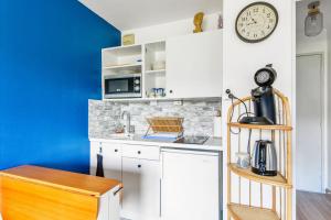 eine Küche mit weißen Schränken und einer Uhr an der Wand in der Unterkunft Charming 1br with sunny balcony - Houlgate - Welkeys in Houlgate