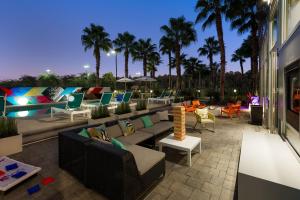 a patio with couches and tables and palm trees at Aloft Jacksonville Airport in Jacksonville