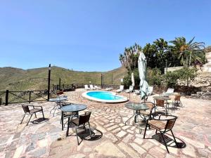 a patio with tables and chairs and a pool at Apto en una casa rural, con cocina, piscina, barbacoa compartidas y vistas en Sur de Tenerife in San Miguel de Abona