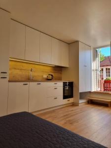 a kitchen with white cabinets and a sink and a window at Pamario Namai in Nida