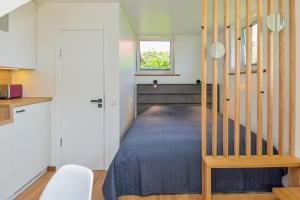 a small bedroom with a bed and a staircase at Pamario Namai in Nida