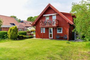 ein rotes Haus mit einem Balkon auf einem Hof in der Unterkunft Pamario Namai in Nida