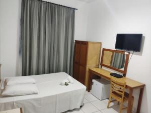 um quarto com uma cama, uma secretária e um espelho em Grande Hotel Bragança em Bragança Paulista