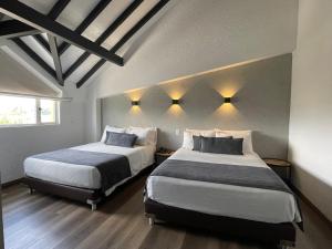 1 dormitorio con 2 camas y luces en la pared en Hotel Santiago de Arma en Rionegro