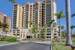 un grand bâtiment avec des palmiers en face d'une rue dans l'établissement Condo with Views and Resort Amenities in Cape Harbour!, à Cape Coral