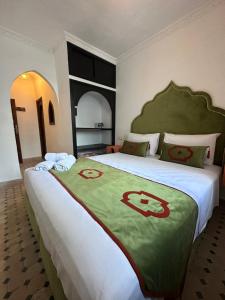 a bedroom with a large bed with a green and white blanket at Kasba blanca in Tangier