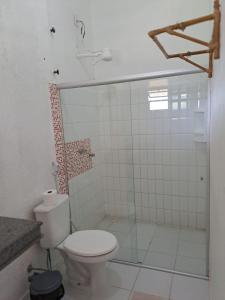a bathroom with a toilet and a glass shower at Pousada Éden Rio in Ilhéus