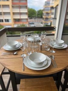 einen Holztisch mit Tellern und Weingläsern darauf in der Unterkunft Belle vue in Cap d'Agde
