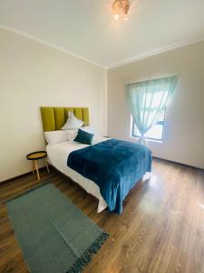 um quarto com uma cama com um cobertor azul e uma janela em Jackal Creek em Joanesburgo