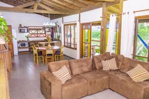 a living room with a brown couch and a table at Pousada Morro das Palmeiras in Praia do Rosa